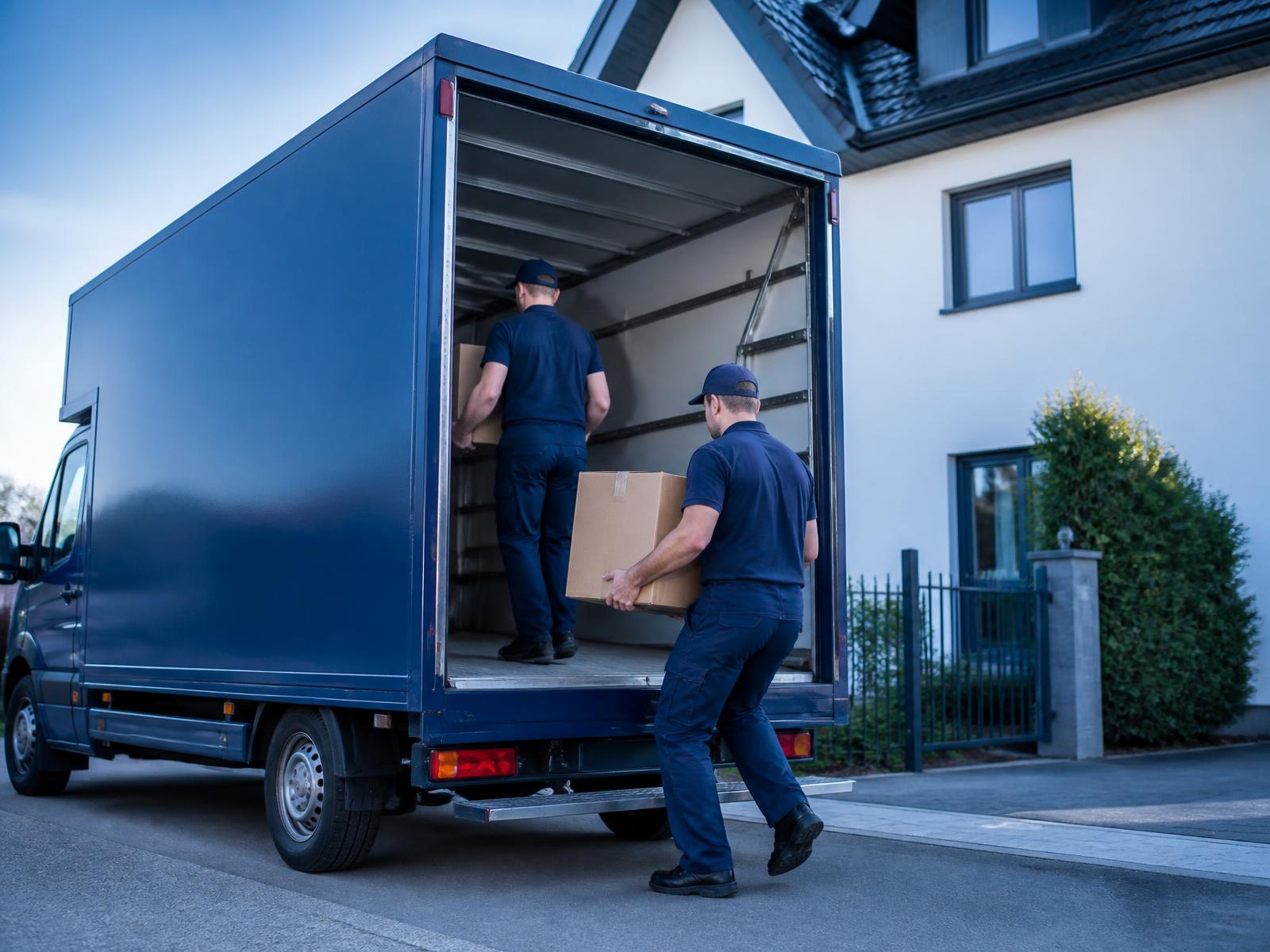Mitarbeiter von RheinTrack tragen Möbel zu einem sauberen Transporter vor einem Wohnhaus